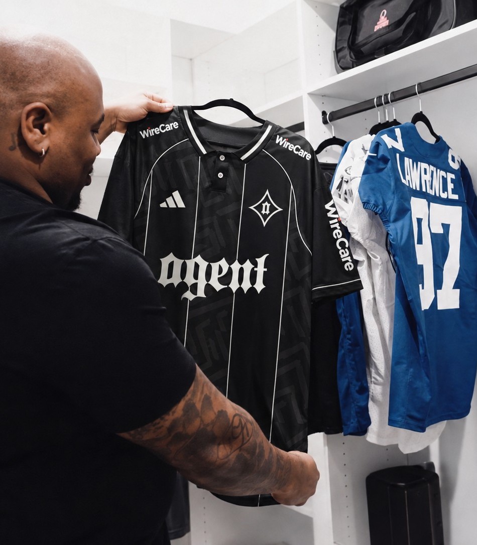 Dexter Lawrence holding the Agent x WireCare jersey beside his Lawrence number 97 jersey